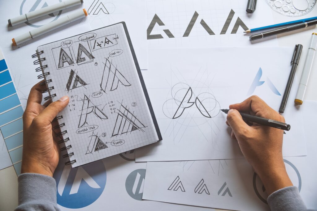 digital marketing branding guide erons hand drawing an A logo while holding a notebook in his left hand with other versions of the a logo | Navazon Digital digital marketing branding guide erons hand drawing an A logo while holding a notebook in his left hand with other versions of the a logo | Navazon Digital