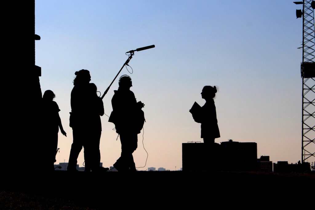 Digital Marketing Video Production arms of a man working on his tablet and working on a video production with a video camera on the camera silhouette of video production team at dusk filming | Navazon Digital
